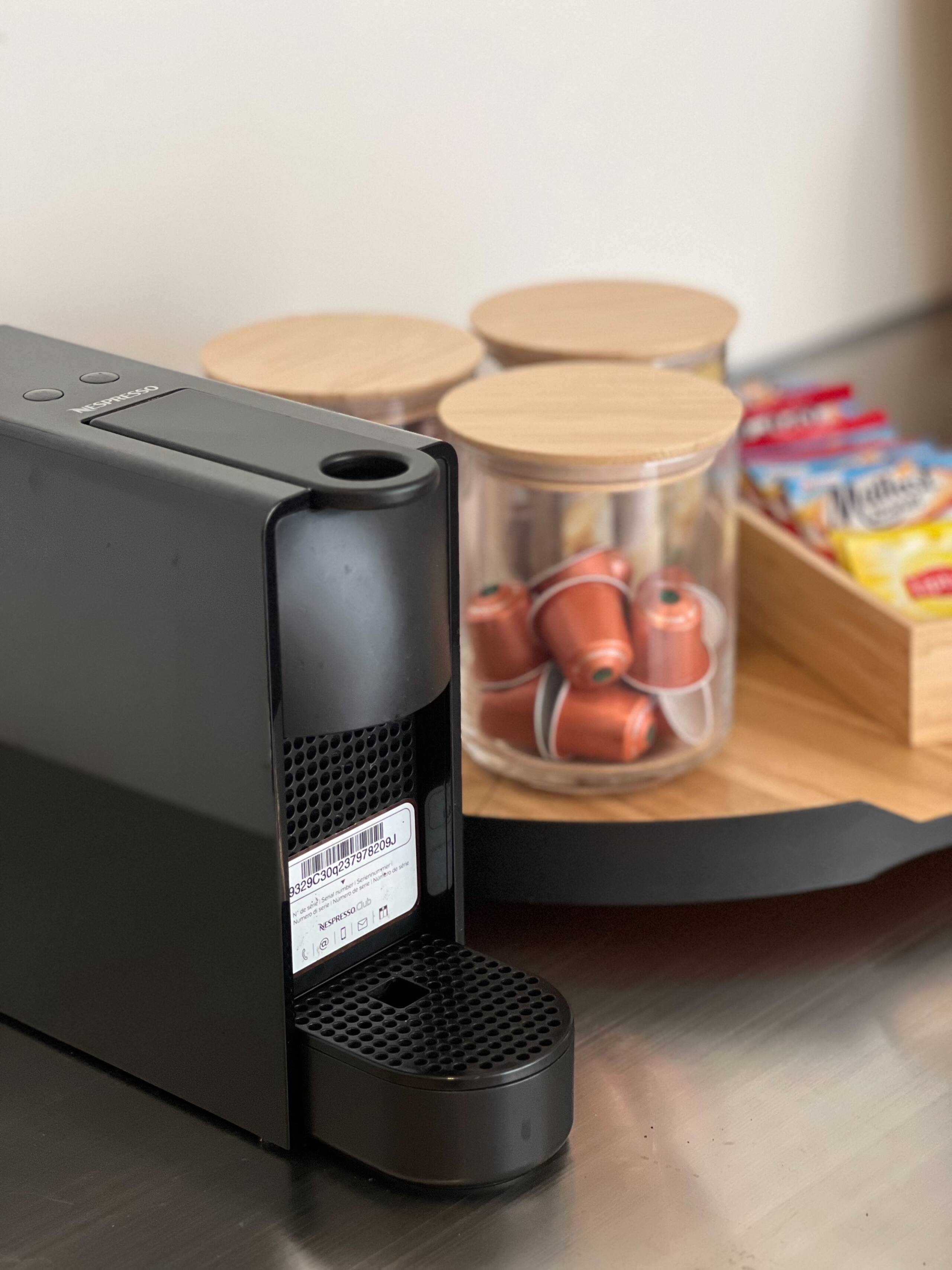Black Nespresso machine with a jar of coffee capsules and tea sachets in the home's coffee corner