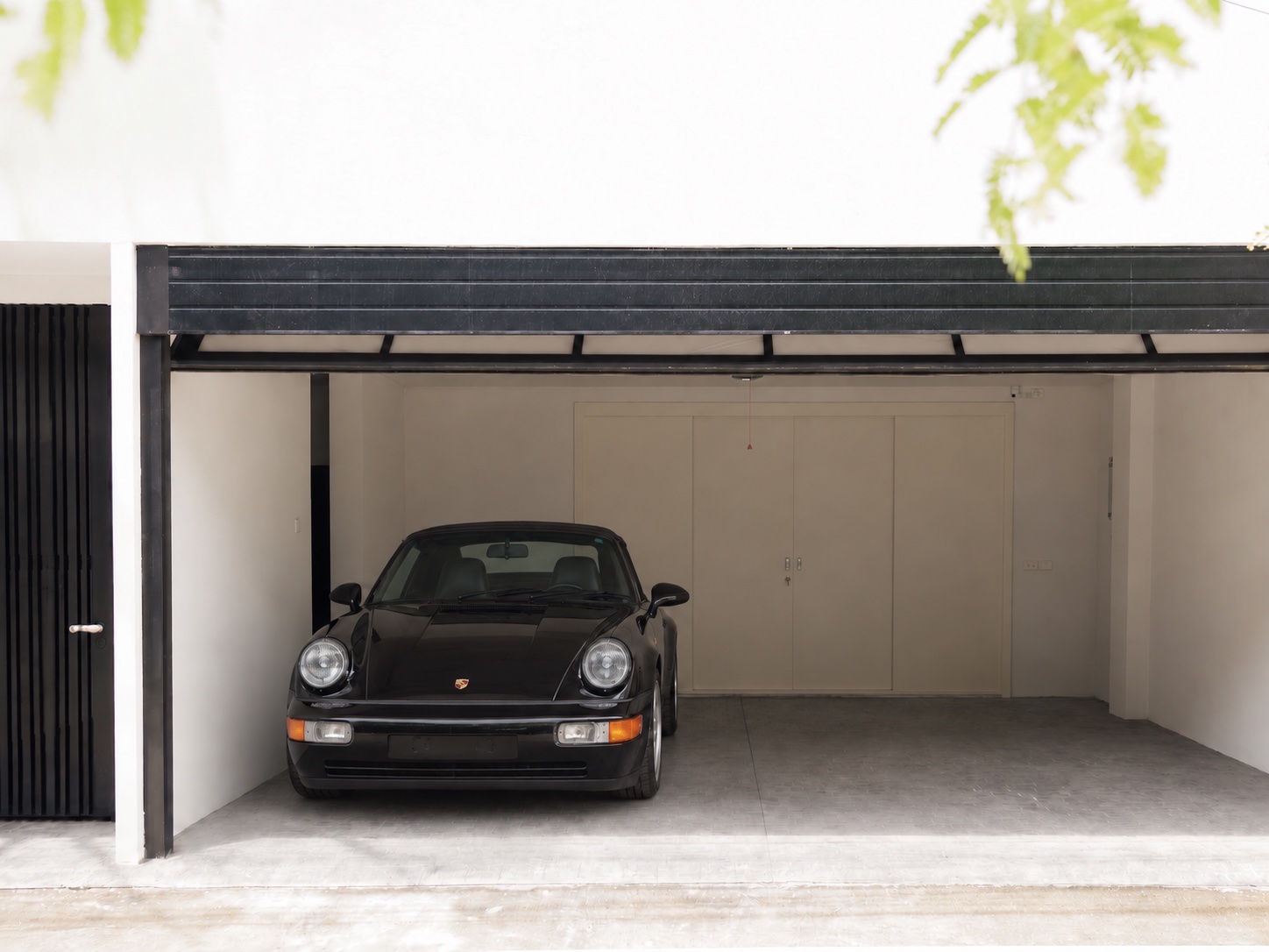 Garage visualization with a black Porsche beside the closed sliding doors to the living room. Vehicle not included with the stay.